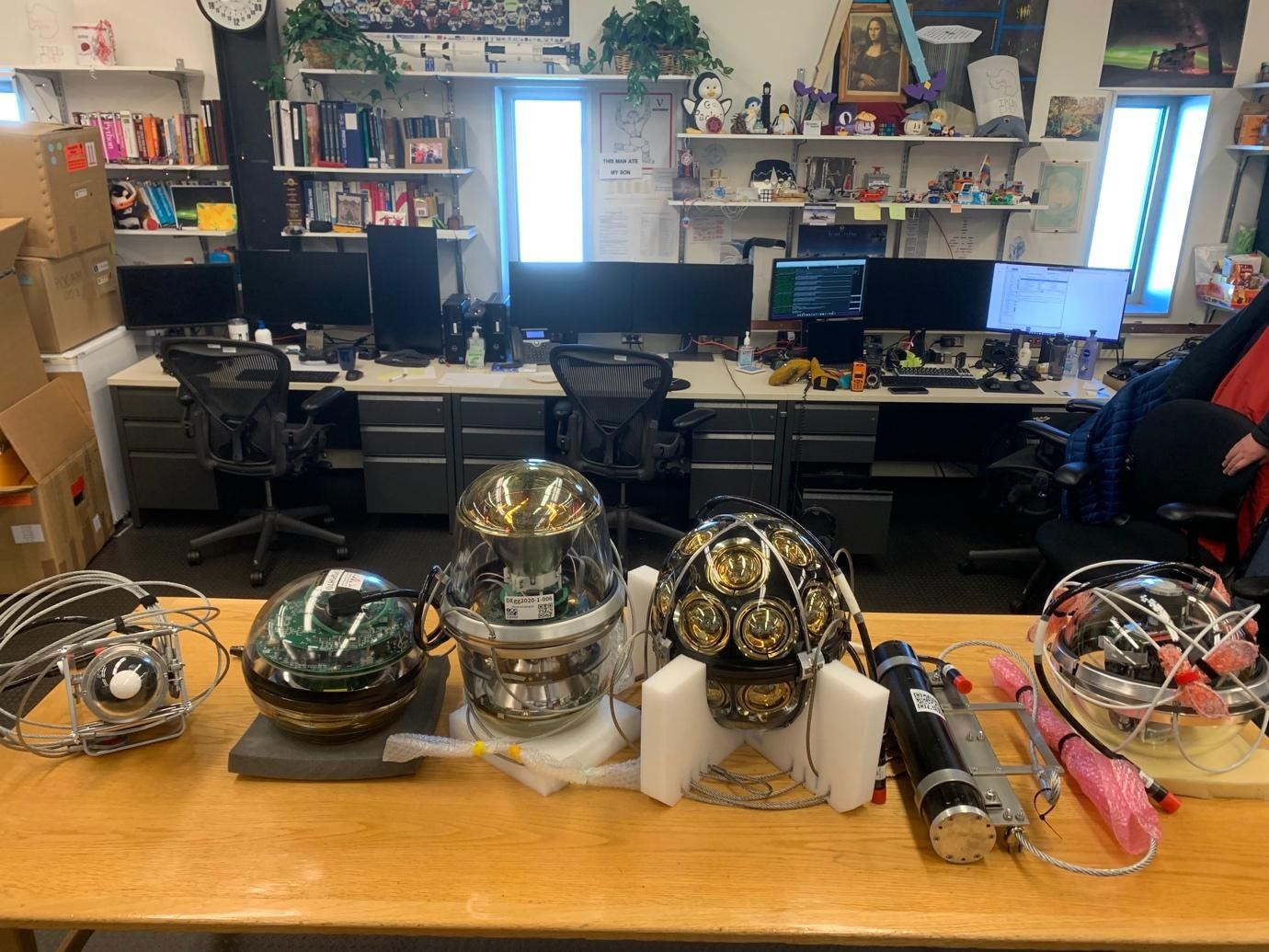 Credit: Sarah Mechbal, IceCube/NSF: DOMs and special devices, including the D-Egg (third from left) and mDOM (fourth fro