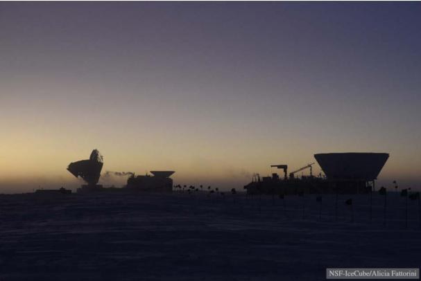 The South Pole Telescope (SPT) on the left and the BICEP telescopes in the center and on the right, just before sunrise.